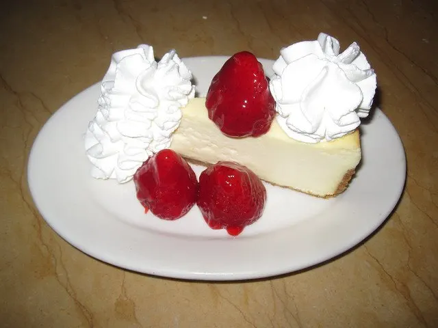 A slice of cheesecake with strawberries and whipped cream