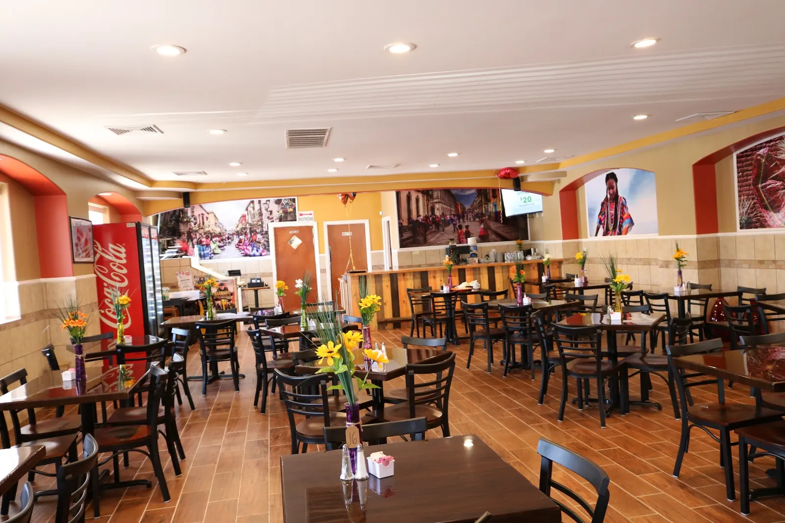 The dining room at Pleasantville Diner, with warm red walls and tables set with flowers